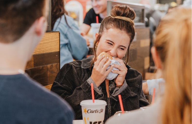 girl eating burger with friends carl's jr.