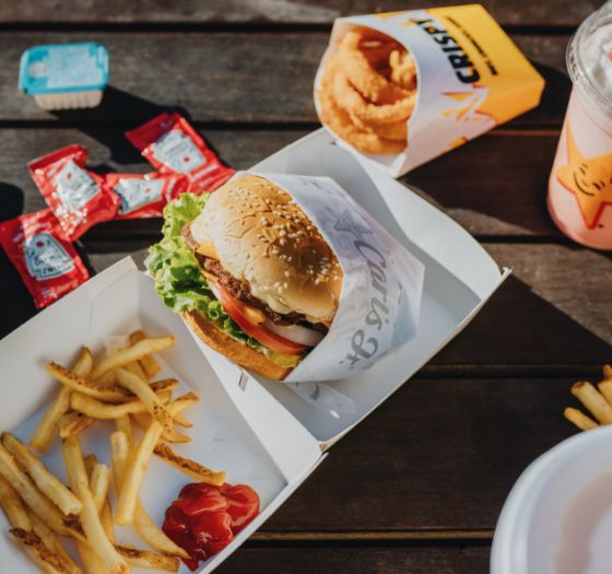 Burger, fries, onion rings, milkshake laid out on a table