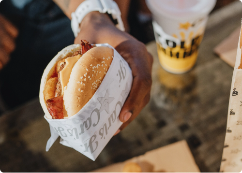 hand holding a burger and fountain drink on the side