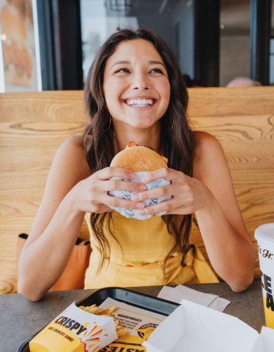 girl smiling with burger in hand